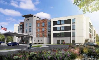 a modern hotel with a red - brick facade and large windows , surrounded by greenery and flowers at Homewood Suites by Hilton Salt Lake City Draper