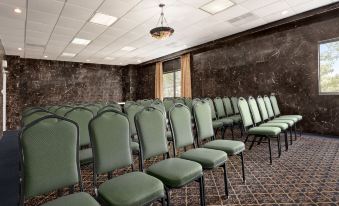 a conference room with rows of green chairs arranged in a semicircle , and a chandelier hanging from the ceiling at Oh St Joseph Resort Hotel