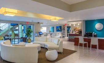 a modern hotel lobby with white furniture , including a couch and chairs , and a dining table at Wyndham Reef Resort Grand Cayman
