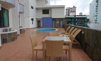 a patio with a table and chairs , a swimming pool , and a building in the background at Hotel Principe