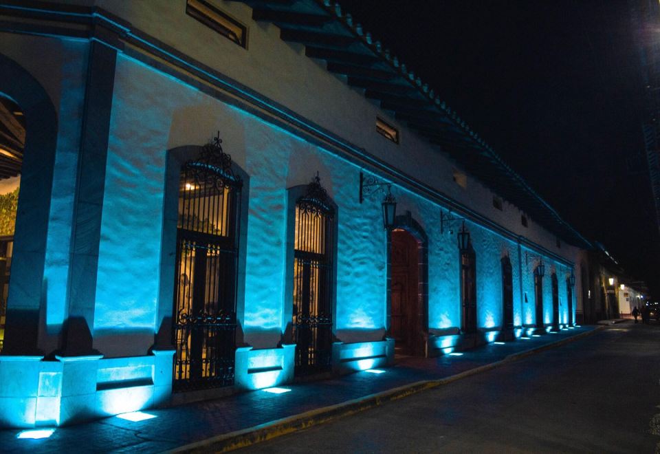 a nighttime scene of a white building with blue lights illuminating the windows , creating an elegant atmosphere at Casa San Miguel Hotel Boutique y Spa