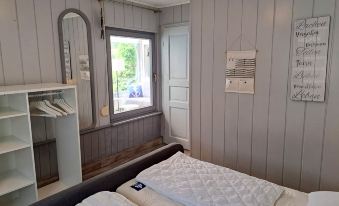 a bedroom with a white bed , gray walls , and a window overlooking a patio at Karli