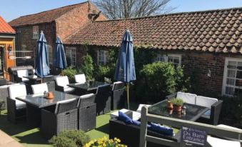 a patio area with a table and chairs , surrounded by umbrellas and a brick building at The Durham Ox