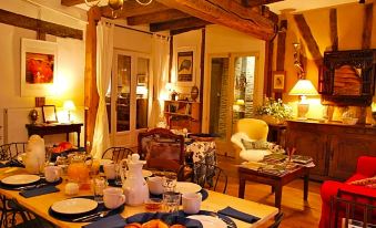 a cozy living room with a wooden table set for breakfast , surrounded by a dining area at Ombre Rose