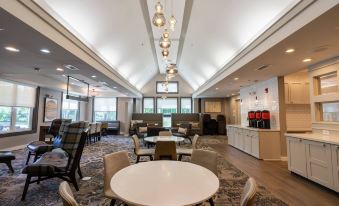 a large , modern hotel lobby with several dining tables and chairs , as well as a bar area at Residence Inn by Marriott Princeton at Carnegie Center