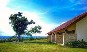 a large house with a red roof sits in a grassy field , surrounded by trees at Tunak Cottage