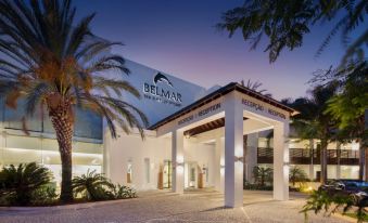 a large white building with palm trees in front of it , possibly a hotel or resort at Belmar Spa & Beach Resort