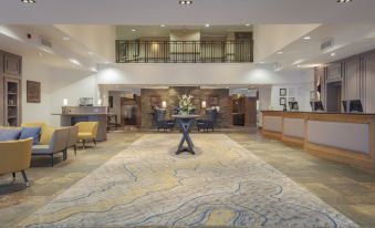 a spacious lobby with a reception desk , chairs , and a large rug , possibly for sale or rent at DoubleTree by Hilton Glasgow Westerwood Spa & Golf Resort