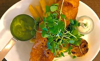 a plate of food on a dining table , consisting of a fish and vegetables , with a variety of sauces at The Pytchley Inn