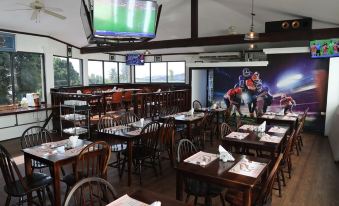 a restaurant with wooden tables and chairs , a television screen , and an aerial view of the sky at Tradewinds Hotel