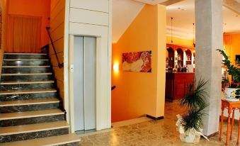 a well - decorated living room with orange walls , marble floors , and a staircase leading to the second floor at Hotel Jasmine