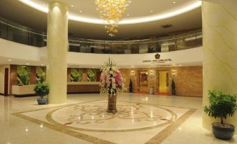 a luxurious hotel lobby with a large circular floral arrangement in the center , surrounded by marble floors and chandeliers at Saigon Vinh Long Hotel