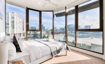 a bedroom with a large window overlooking a cityscape , featuring a bed and a ceiling fan at Capri