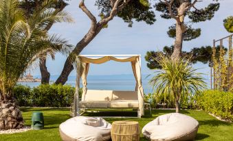 a lush green lawn with a canopy bed and two bean bag chairs placed in the middle at Valamar Meteor Hotel