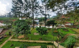 a lush green garden with a variety of trees and plants , as well as a body of water nearby at Marbella Twin Waterfall Resort Ciater