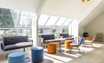 a modern lounge area with a variety of seating options , including couches , chairs , and ottomans at Best Western Armor Park Dinan