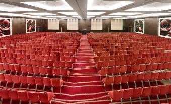 a large conference room with rows of red chairs and a stage at the front at Park Plaza Westminster Bridge London