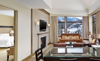 a modern living room with a dining table and chairs , a fireplace , and a flat - screen tv . also a fireplace in the room at The Westin Riverfront Resort & Spa, Avon, Vail Valley