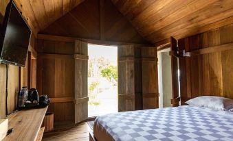 a bedroom with wooden walls and a checkered bedspread , leading to an open door that leads outside at Berugo Cottage
