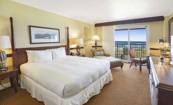 a large bed with white linens is in a hotel room with a sliding glass door leading to a balcony at OUTRIGGER Kaua'i Beach Resort & Spa