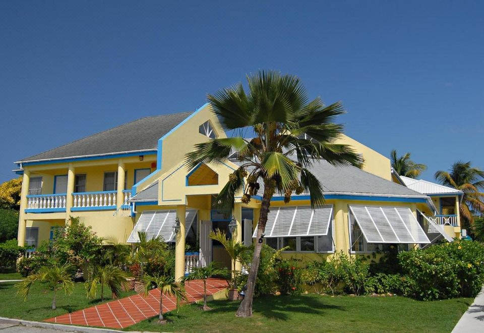 a yellow and blue house with a palm tree in front of it , surrounded by green grass at Anchorage Inn