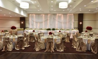 a large banquet hall with multiple round tables and chairs set up for a formal event , possibly a wedding reception at Four Points by Sheraton Winnipeg South