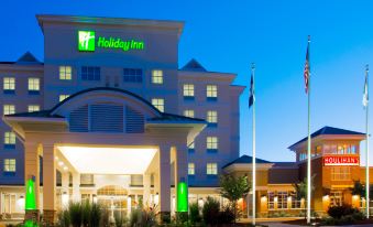 "a large hotel with a green sign that says "" holiday inn "" is shown at night" at DoubleTree by Hilton Front Royal Blue Ridge Shadows