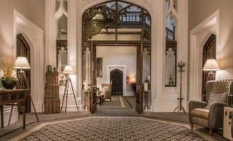 a grand entrance to a hotel , with large ornate arches and a carpeted floor leading to a well - appointed room at De Vere Tortworth Court