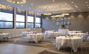 a large , well - lit banquet hall with numerous tables and chairs set up for a formal event at Hôtel du Port