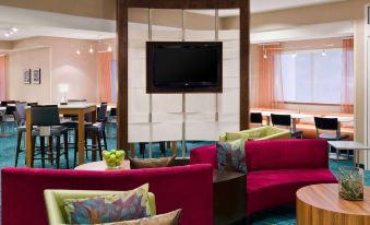 a living room with a large flat - screen tv mounted on the wall , surrounded by couches and chairs at Sonesta Select Seattle Renton Suites