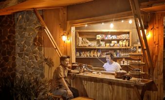 a wooden bar with a man sitting at the counter , surrounded by bottles and glasses at Villa Sindoro Village