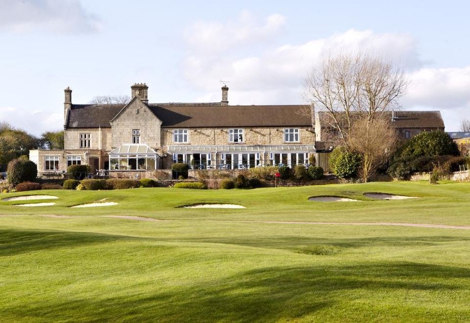 a large house with a thatched roof and multiple windows is surrounded by green grass and trees at Horsley Lodge