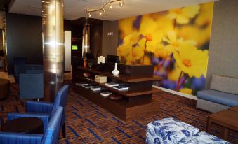 a hotel lobby with a check - in desk and a large mural on the wall behind it at Courtyard Philadelphia Bensalem