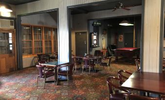 a large room with a red carpeted floor and several tables and chairs , featuring wooden floors and pendant lights at Hotel Kerwick