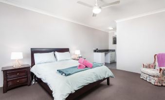 a clean , white bedroom with a large bed and a bathroom nearby , under a ceiling fan at Archibald Hotel