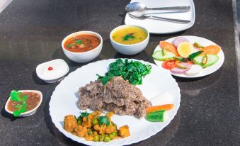 a dining table with a variety of food items , including meat , vegetables , and other dishes at Green Leaf Resort