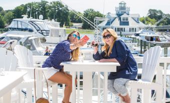 two women sitting at a table on a boat , enjoying drinks and taking pictures of each other at Smithfield Station