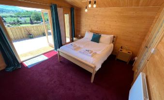 a cozy bedroom with a wooden bed and red carpet , featuring a large window and a view of the outdoors at Three Wheat Heads