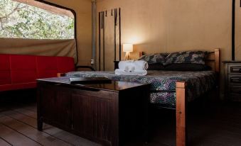 a cozy bed with a wooden headboard and footboard , surrounded by white sheets and a matching comforter , in a tent - like room at Breeze Holiday Parks - Mary River