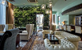 a living room with a couch , chairs , and a coffee table in front of a wall covered in plants at Hotel Continental
