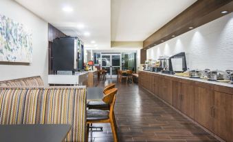 a modern hotel lobby with wooden floors , high ceilings , and a large dining area with various furniture pieces at Wyndham Garden Washington DC Area