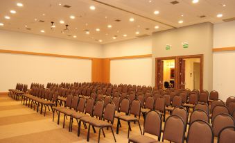a large conference room with rows of chairs arranged in front of a projector screen at Bourbon Cambara Hotel