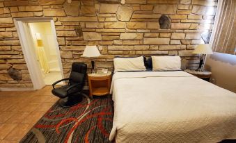 a hotel room with a bed , desk , and chair , as well as a stone wall at Jefferson Hills Motel