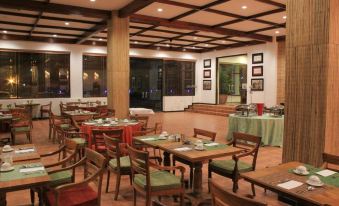 a well - lit dining room with wooden tables and chairs , along with a fireplace in the background at Hotel Timor