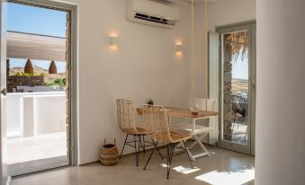 a white room with a table and chairs , an air conditioner , and sliding glass doors at The Summit of Mykonos