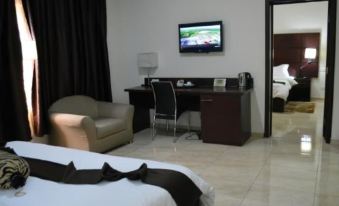 a modern hotel room with a bed , desk , and tv , along with black curtains and white bedding at De Santos Hotel