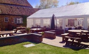a large white tent is set up in a grassy area with tables and benches at St Quintin Arms