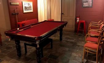 a red pool table with a white cue stick in the center of a room at Cottonwood Lodge