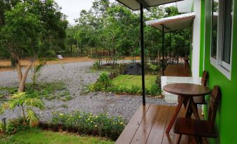 a wooden deck with a view of a lush green garden and trees , seen from the outside at Piamsuk Resort