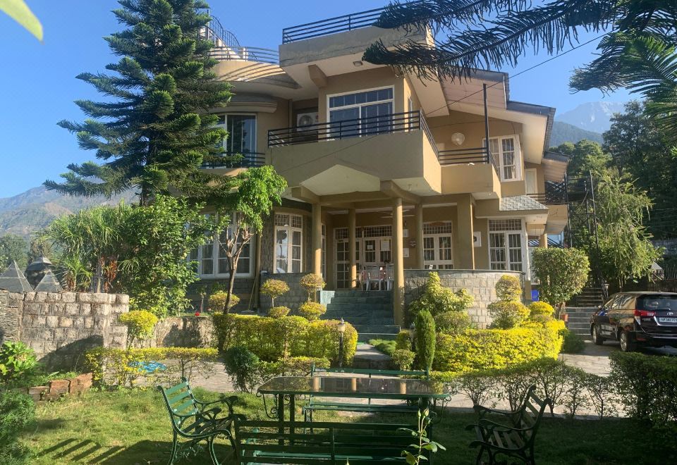 a large , two - story house with a balcony and green lawn furniture in front of it at The Sojourn